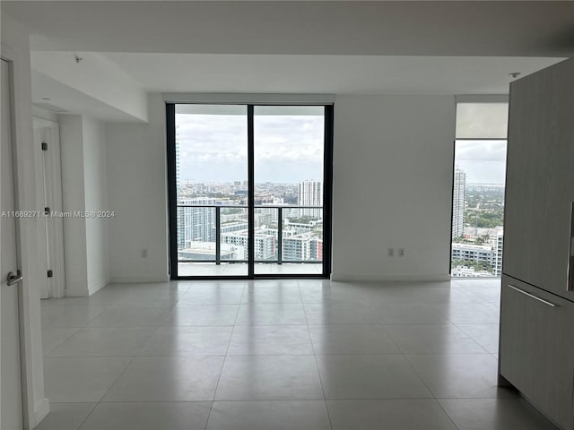 tiled empty room with expansive windows and a healthy amount of sunlight