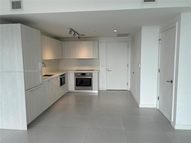 kitchen featuring light tile patterned floors, black stovetop, oven, and sink