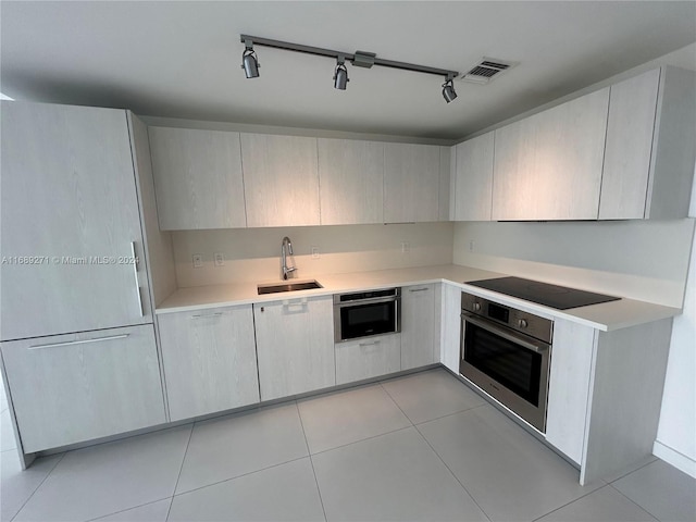 kitchen with sink, light tile patterned floors, track lighting, and stainless steel appliances