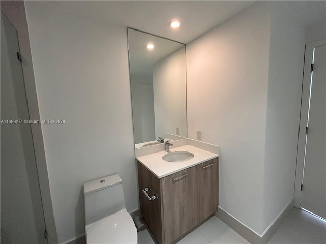 bathroom with toilet, vanity, and tile patterned floors