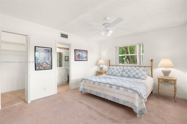 carpeted bedroom with a textured ceiling, ensuite bath, ceiling fan, and a closet