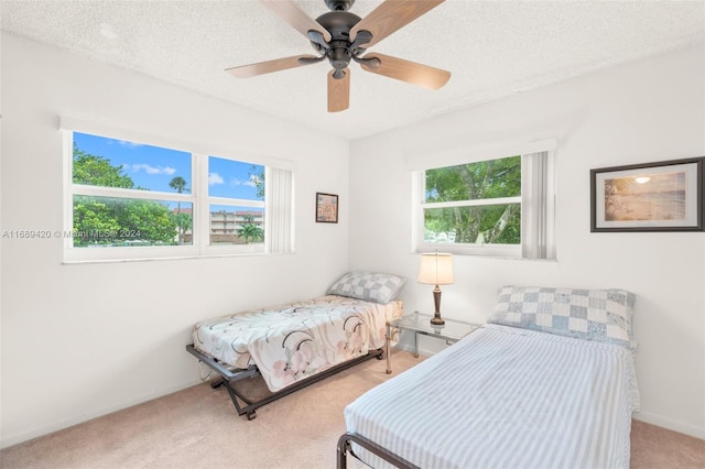 carpeted bedroom with ceiling fan and a textured ceiling