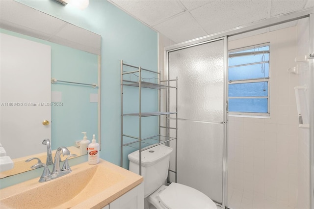 bathroom with walk in shower, a paneled ceiling, vanity, and toilet