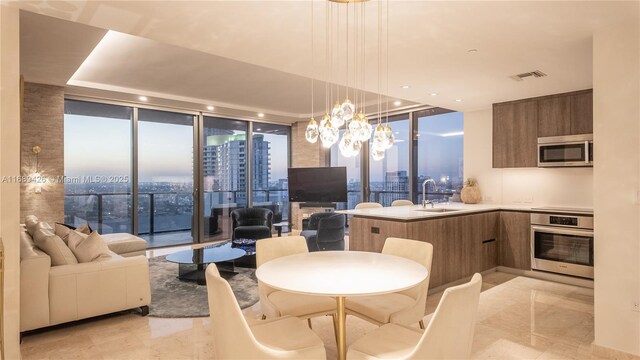 kitchen featuring sink, decorative light fixtures, a notable chandelier, a wall of windows, and stainless steel appliances