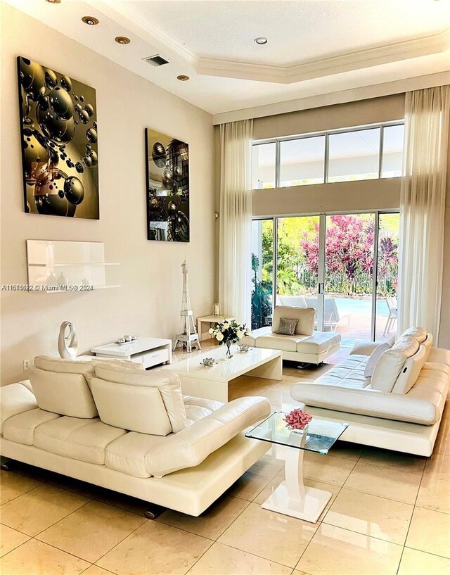 living room with light tile patterned floors, ornamental molding, and a raised ceiling