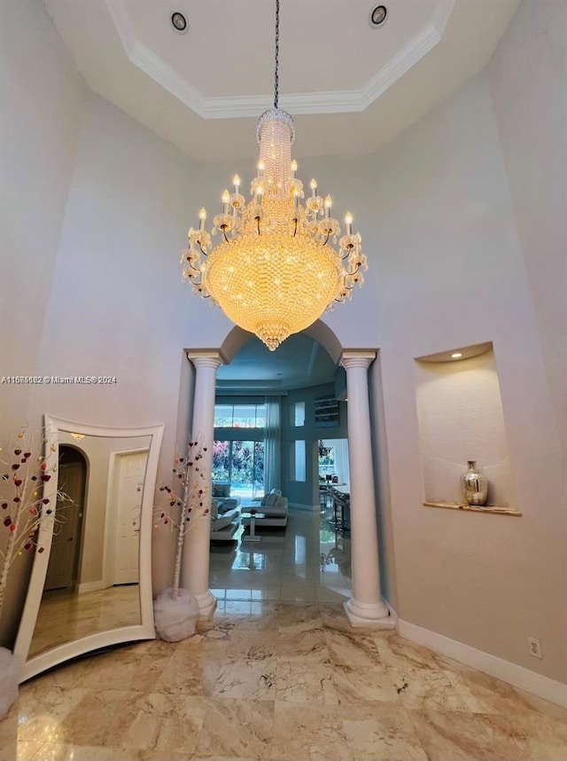 hall with decorative columns, an inviting chandelier, and crown molding