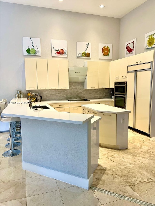 kitchen featuring extractor fan, sink, kitchen peninsula, stainless steel double oven, and paneled fridge