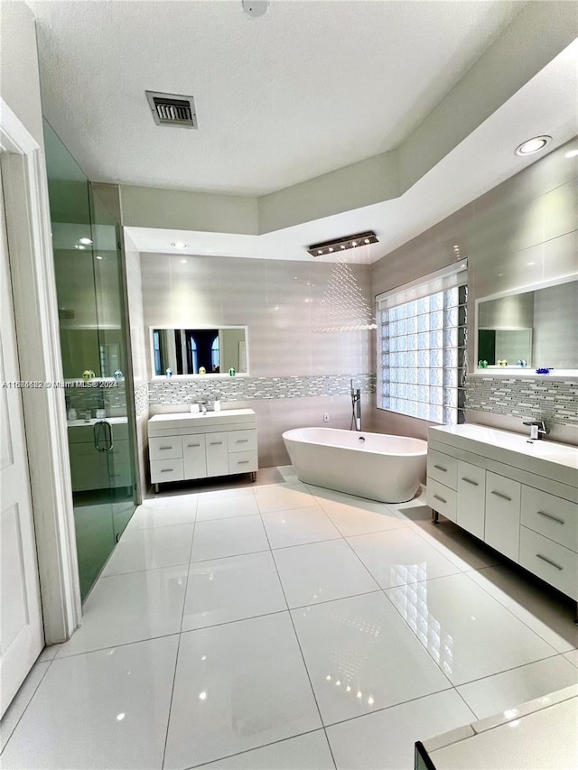 bathroom featuring tile patterned floors, vanity, a textured ceiling, plus walk in shower, and decorative backsplash