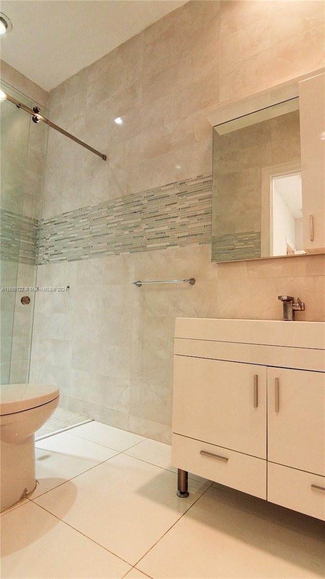 bathroom featuring tile walls, tile patterned floors, vanity, toilet, and a shower with shower door