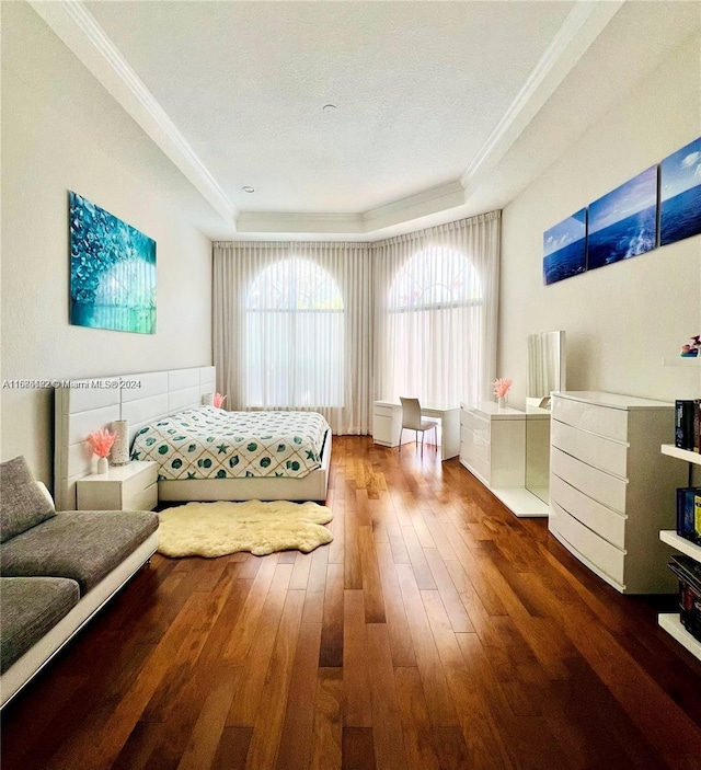 bedroom with hardwood / wood-style floors, a raised ceiling, and crown molding