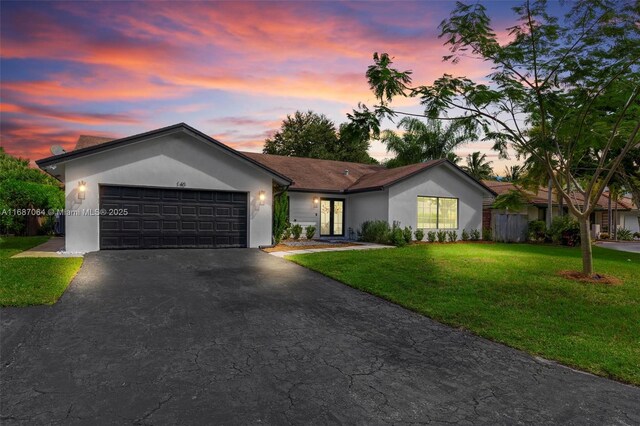 ranch-style home with a garage and a yard