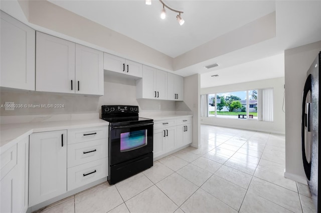 kitchen with white cabinets, fridge, and black electric range