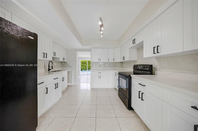 kitchen with sink, rail lighting, electric range, light tile patterned flooring, and white cabinetry