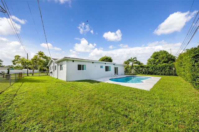 rear view of house featuring a fenced in pool and a lawn