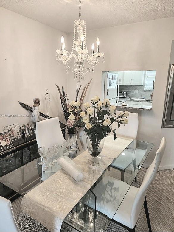 carpeted dining area with a textured ceiling and a notable chandelier