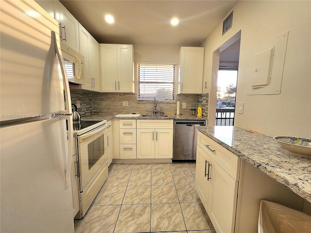 kitchen featuring light tile patterned flooring, sink, white cabinets, light stone counters, and white appliances