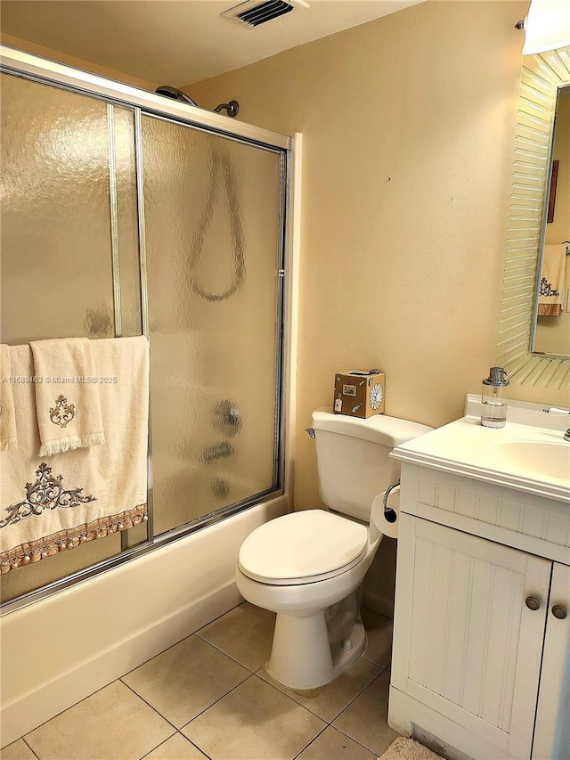 full bathroom featuring vanity, bath / shower combo with glass door, tile patterned floors, and toilet