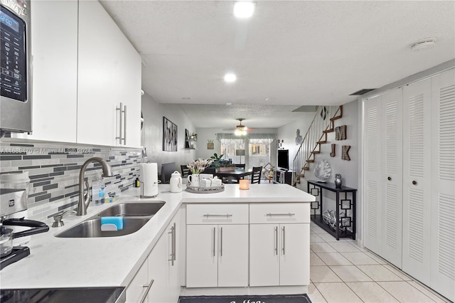 kitchen with white cabinets, light tile patterned floors, sink, and kitchen peninsula