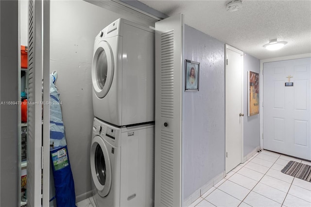 laundry area featuring stacked washer and dryer, a textured ceiling, and light tile patterned floors