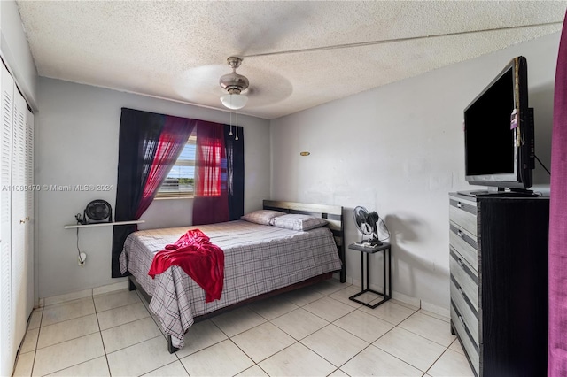 tiled bedroom with ceiling fan, a textured ceiling, and a closet