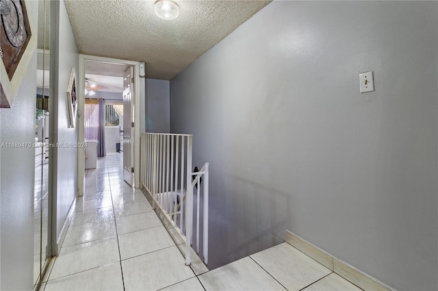 hall featuring light tile patterned flooring and a textured ceiling