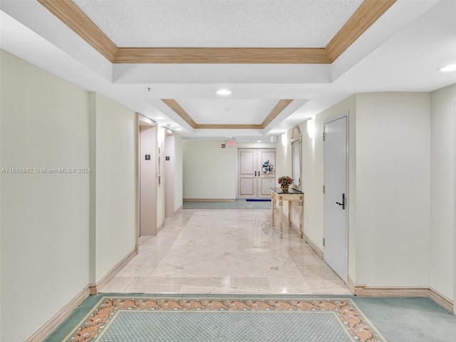 hallway with ornamental molding, a textured ceiling, and a tray ceiling