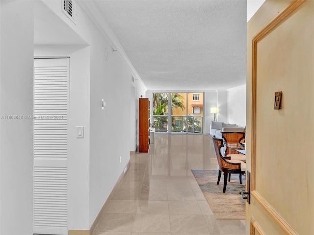 hall with floor to ceiling windows, a textured ceiling, and ornamental molding