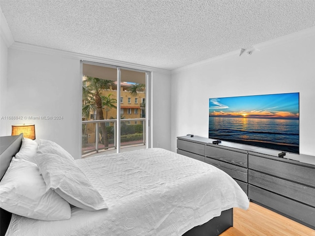 bedroom with a textured ceiling, light wood-type flooring, and crown molding