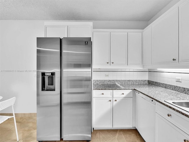 kitchen with backsplash, white dishwasher, stainless steel fridge, light tile patterned floors, and white cabinetry