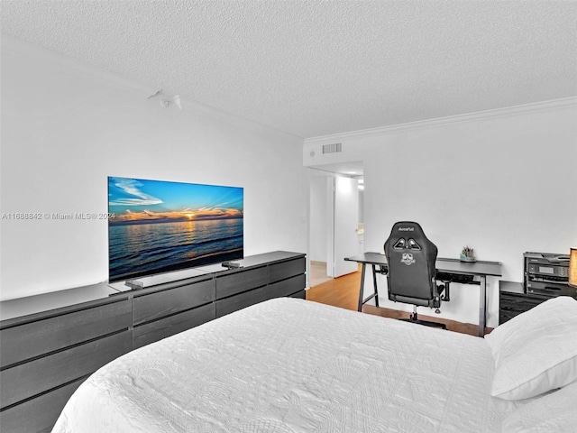 bedroom with crown molding, light wood-type flooring, and a textured ceiling