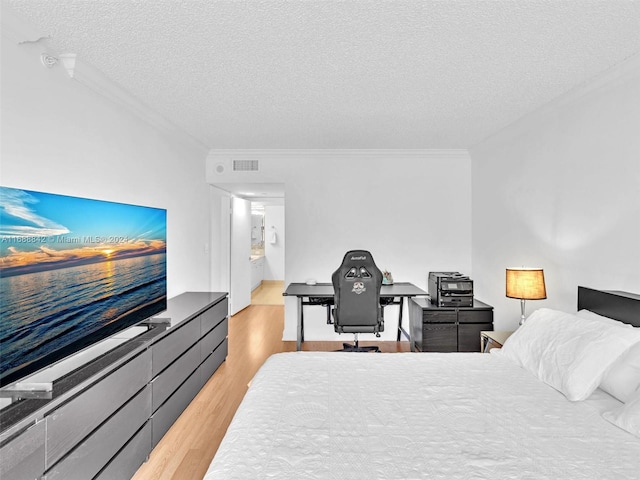 bedroom featuring ornamental molding, a textured ceiling, and light hardwood / wood-style flooring