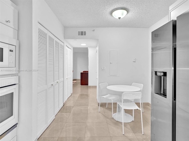 hall with light tile patterned flooring and a textured ceiling