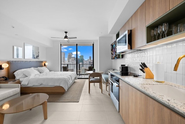 bedroom with floor to ceiling windows, sink, light tile patterned floors, access to outside, and ceiling fan