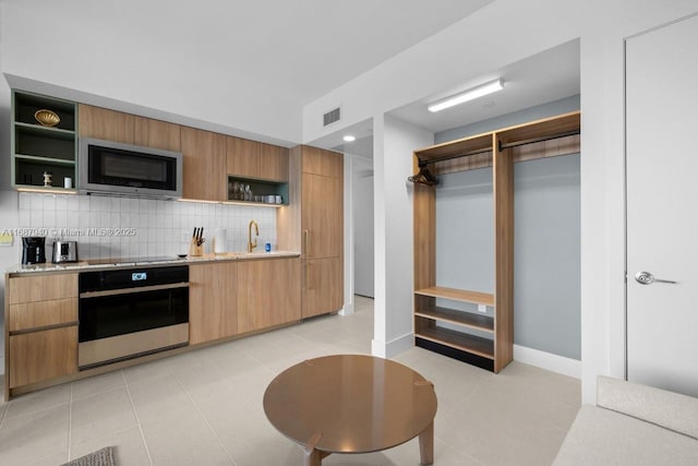 kitchen featuring tasteful backsplash, light stone counters, and stainless steel appliances