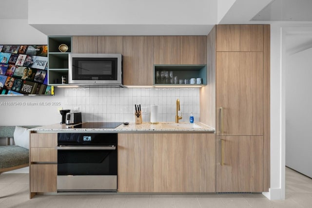 kitchen featuring sink, stainless steel appliances, light stone counters, light brown cabinetry, and decorative backsplash