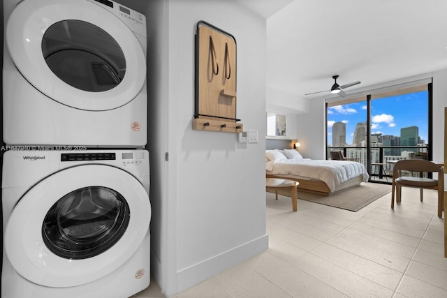 laundry room with ceiling fan, stacked washer / dryer, and light tile patterned floors