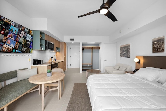 bedroom featuring sink, light tile patterned floors, ceiling fan, and a closet