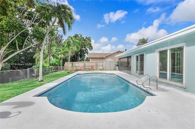 view of swimming pool featuring a lawn, a patio area, and a shed