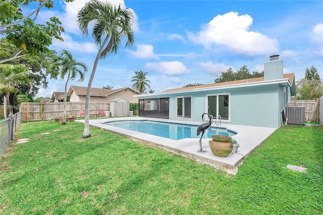 view of pool with a yard, central AC unit, and a storage unit