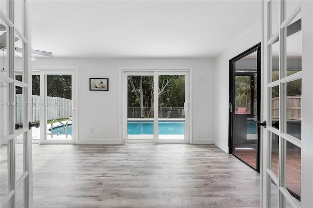 empty room featuring a healthy amount of sunlight, light hardwood / wood-style floors, and french doors