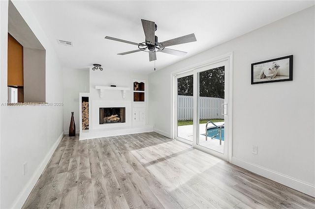 unfurnished living room with ceiling fan, light wood-type flooring, and built in features