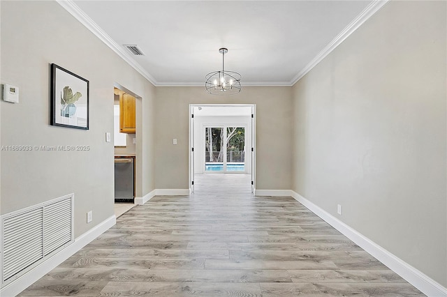 unfurnished dining area with light hardwood / wood-style flooring, ornamental molding, and a notable chandelier