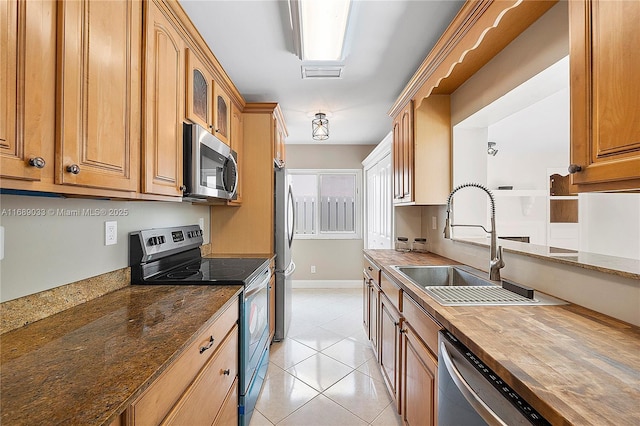 kitchen featuring wood counters, light tile patterned flooring, sink, and appliances with stainless steel finishes