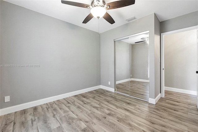 unfurnished bedroom with ceiling fan, light wood-type flooring, and a closet