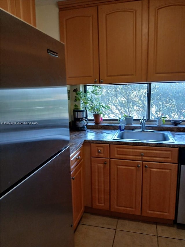 kitchen with stainless steel refrigerator, light tile patterned flooring, and sink