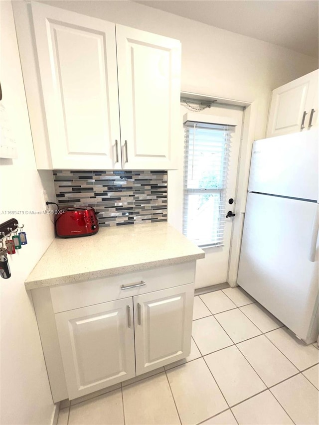 kitchen with white cabinets, light tile patterned floors, tasteful backsplash, and white fridge