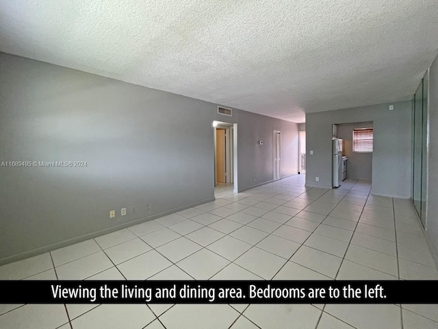 empty room with a textured ceiling and light tile patterned floors