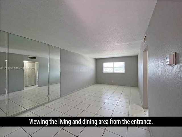 unfurnished room with light tile patterned flooring and a textured ceiling