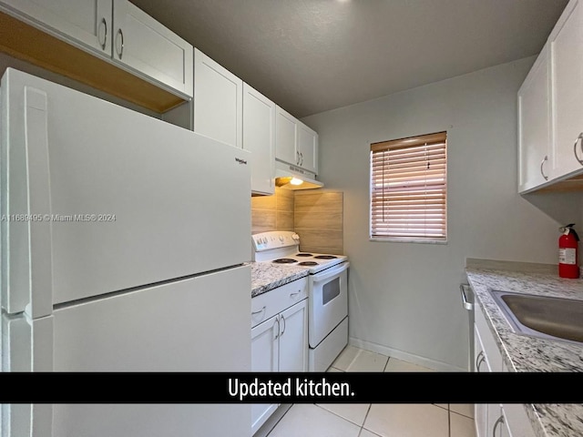 kitchen with white cabinetry, light stone counters, and white appliances