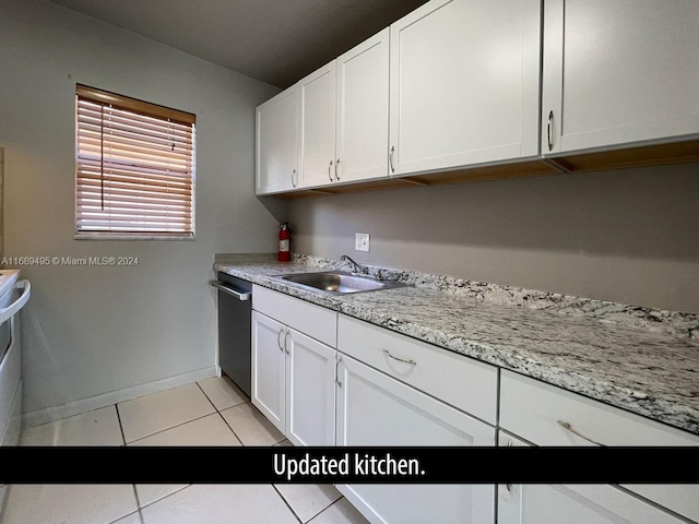 kitchen featuring white cabinets, dishwasher, light tile patterned floors, sink, and light stone countertops